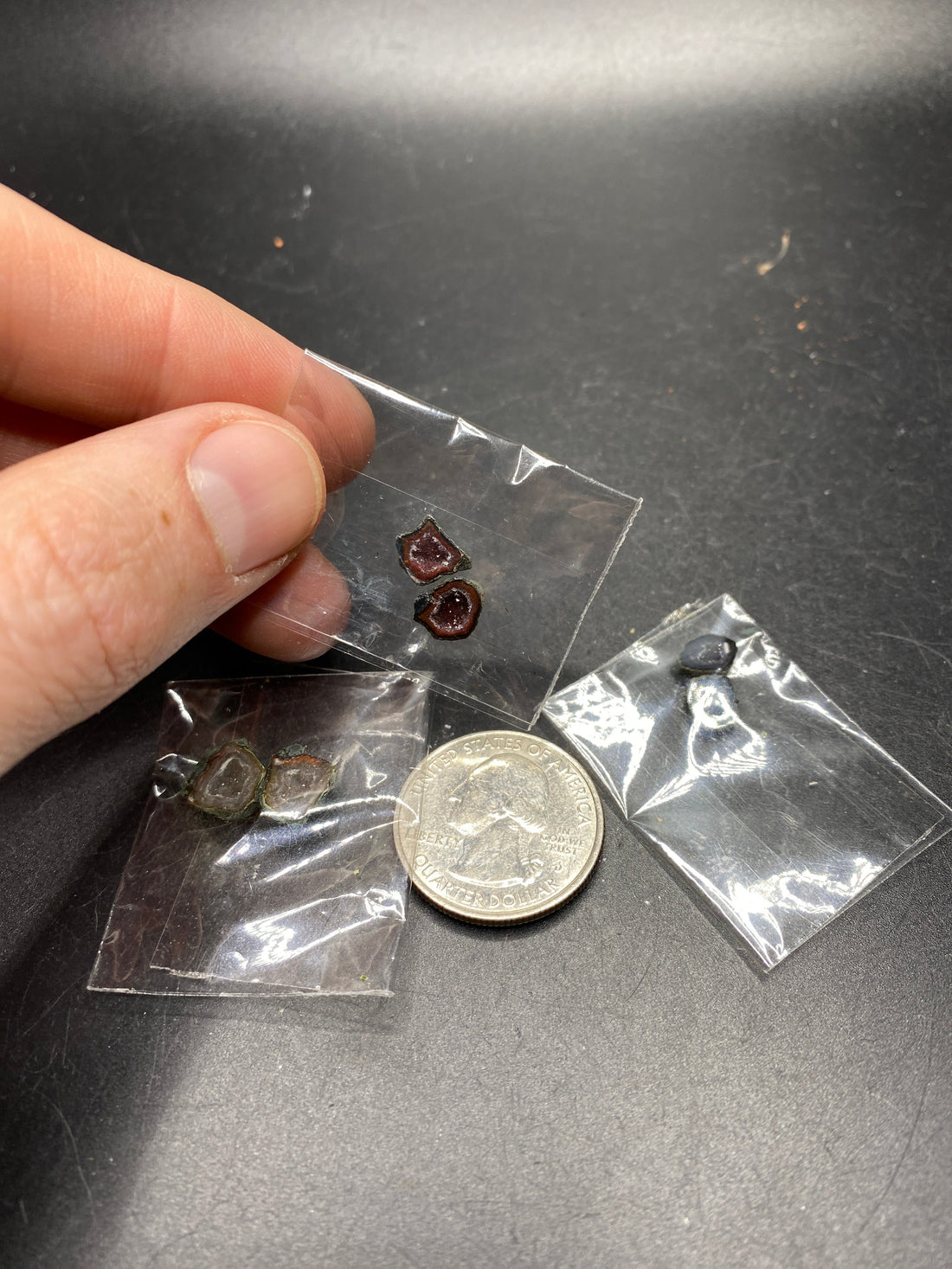 Small Tabasco geode pairs in clear bags beside a U.S. quarter, with one bag held between fingers for scale.